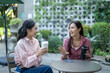 © Wasana - Women friends enjoying conversation and coffee in outdoor cafe