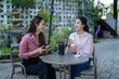 © Wasana - Young women friends talking and drinking coffee outside cafe