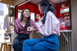 © Wasana - Two women friends enjoying conversation at food stall
