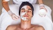 © David Zarzosa - Man receiving professional facial mask treatment at spa skincare clinic.