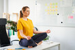 © baranq - Woman meditating in lotus position on office desk during work break