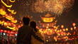 © rabbit75_fot - Chinese traditional lunar new year Spring Festival celebration in Asia. Two people, a man and a woman, standing in front of a temple illuminated by a vibrant display of fireworks.