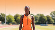 © OlgaNeuroArt - Portrait of a Black female athlete on a running track. Professional runner in orange sportswear at a stadium. Sports and fitness concept