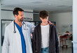 © Halfpoint - Doctor walking with teenage patient after successful medical procedure in hospital.