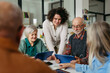 © Halfpoint - Volunteer teaching seniors how to recognize fake news on digital tablet.