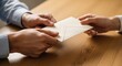 © Your Stock Studio - Hands exchanging a white envelope on a wooden table with copy space
