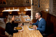 © BGStock72 - Couple enjoys dinner at restaurant with wine and food in evening setting