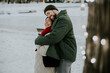 © BGStock72 - Couple shares a warm embrace in snowy setting during winter evening stroll