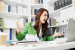 © Pattra - A woman is sitting at a desk with a laptop and a stack of papers. She is angry and yelling at the laptop