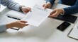 © Rakibul - Two people exchanging a contract on a white table with office supplies.