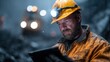 © svastix - A dedicated miner in a rugged environment, sporting a yellow hard hat and illuminated forehead lamp, scrutinizes his tablet amid challenging mining conditions.