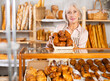 © JackF - Elderly bakery saleswoman places fresh hot croissants on display