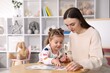 © New Africa - Mother and her daughter playing with toys at wooden table indoors