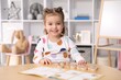 © New Africa - Cute little girl playing with toys at wooden table indoors