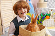 © New Africa - Little boy holding wicker basket with cute Easter bunny indoors