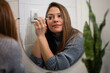 © Zoran Jesic - Woman applying eyebrow pencil in bathroom mirror