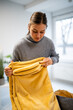 © Zoran Jesic - Woman folding yellow fuzzy blanket at home