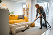 © Zoran Jesic - Woman vacuuming living room carpet for home cleaning