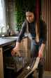 © Zoran Jesic - Woman loading dishwasher with glasses in modern kitchen