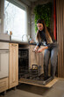 © Zoran Jesic - Woman loading dishwasher with utensils in kitchen