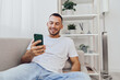 © SHOTPRIME STUDIO - Happy man interacting with smartphone, casual setting, modern interior, enjoying leisure time, positive mood, digital lifestyle.