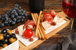© Pixel-Shot - Board with slices of tasty jamon, Grissini and pieces of cheese on wooden background, closeup
