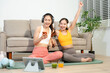 © Nuttapong punna - Two women enjoying home workout on yoga mat with headphones and mobile devices. Healthy lifestyle, fitness, wellness