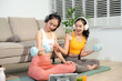 © Nuttapong punna - Two women exercising at home with dumbbells, yoga mat and headphones. Digital workout, fitness lifestyle, wellness and healthy living
