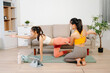 © Nuttapong punna - Two women practicing yoga at home with a personal trainer. Indoor fitness workout, stretching and wellness lifestyle using online guidance