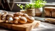 © Plaifah - Fresh mushrooms on a wooden cutting board in a bright kitchen setting with natural light and green plants in the background for culinary inspiration