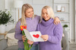 © Pixel-Shot - Pretty young woman and her mother with bouquet of tulip flowers and greeting card at home