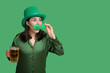 © Pixel-Shot - Beautiful young woman in leprechaun hat and decorative glasses in shape of clover with glass of beer on green background. St. Patrick's Day celebration