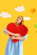 © Pixel-Shot - Young woman with heart near decorated yellow wall. Valentine's Day celebration