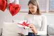 © Pixel-Shot - Beautiful woman opening gift box at home on Valentine's Day
