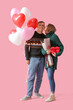 © Pixel-Shot - Lovely couple with bouquet of flowers, gift box and heart-shaped balloons on pink background. Valentine's Day celebration