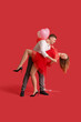 © Pixel-Shot - Lovely couple with heart-shaped balloons dancing on red background. Valentine's Day celebration