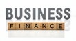 © Mr Artist  - Business finance concept with wooden blocks spelling finance in front of blurred business text