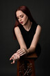 © faestock - close up portrait of beautiful female model with long red hair and black shirt, gestural hand and arm poses, leaning on wooden plinth. classic studio portrait on dark background.