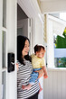 © NZstockphoto - Asian mum standing in porch doorway carrying baby daughter