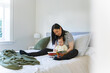 © NZstockphoto - Asian mum reading a book to toddler daughter in bed