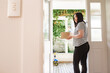© NZstockphoto - Asian woman picking up a package left at the doorstep