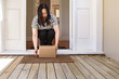 © NZstockphoto - Asian woman picking up a package left at the doorstep