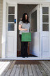 © NZstockphoto - Asian woman picking up a package in green paper bag left at the doorstep