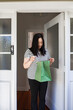 © NZstockphoto - Asian woman picking up a package in green paper bag left at the doorstep