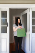 © NZstockphoto - Asian woman picking up a package in green paper bag left at the doorstep