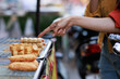 © Phimwilai - Hand pointing at street food for sale outdoors