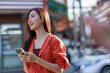 © Phimwilai - Young asian woman smiling using smartphone in city