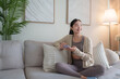 © crizzystudio - Young woman relaxing on sofa using smartphone at home