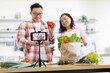 © sofiko14 - A smiling couple records a cooking video in their bright, modern kitchen