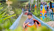 © Kunlathida - Happy smiling Asian little boy looking at the camera and rowing a boat on a water ride